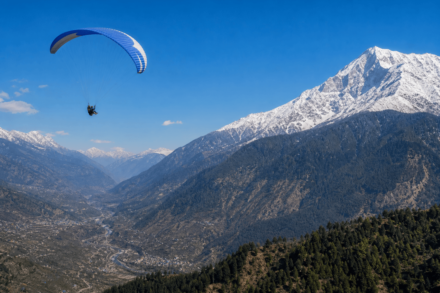 Tandem paraglider flying above the Kullu valley near Dobhi