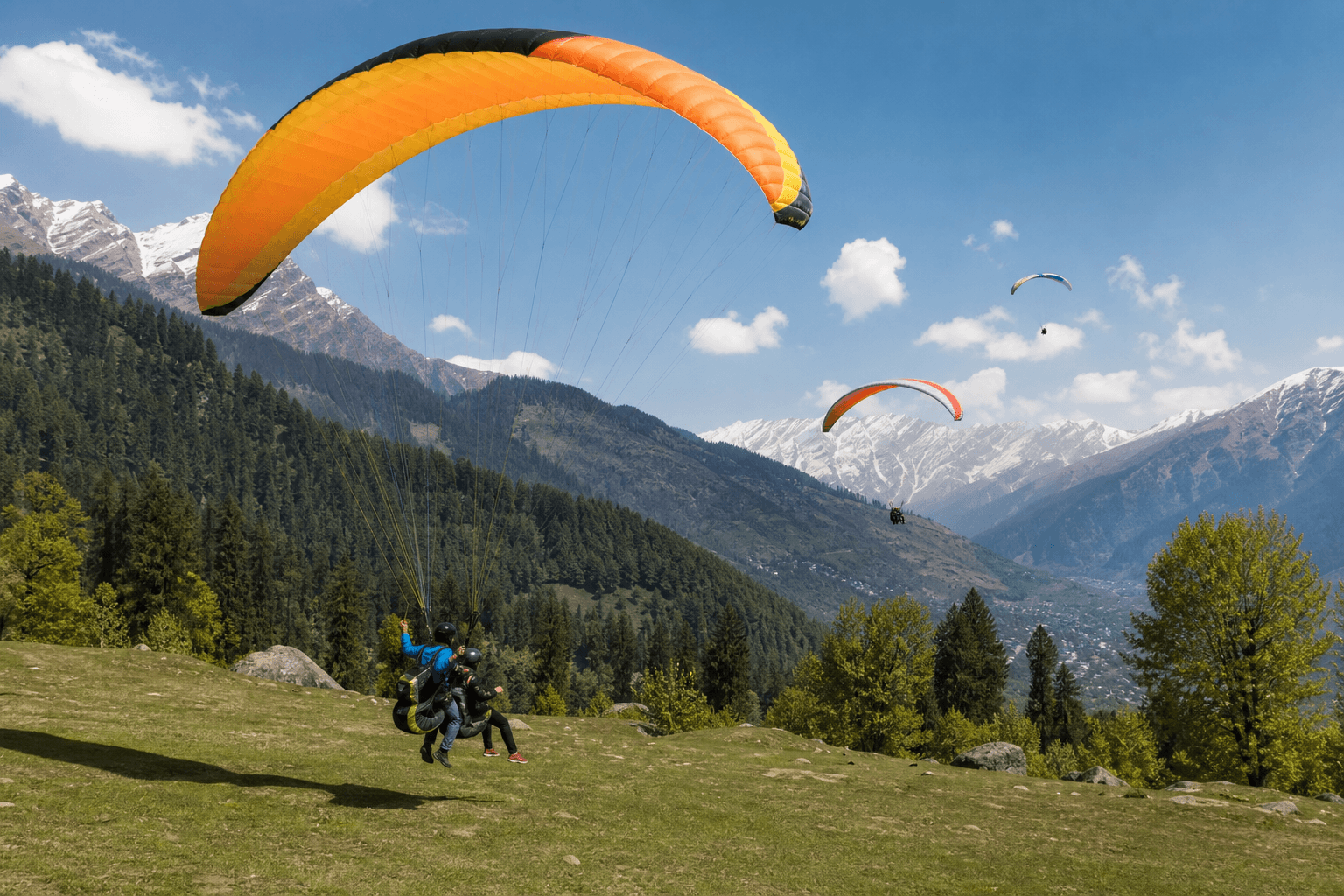 Tandem paragliders launching over the green meadows of Solang Valley